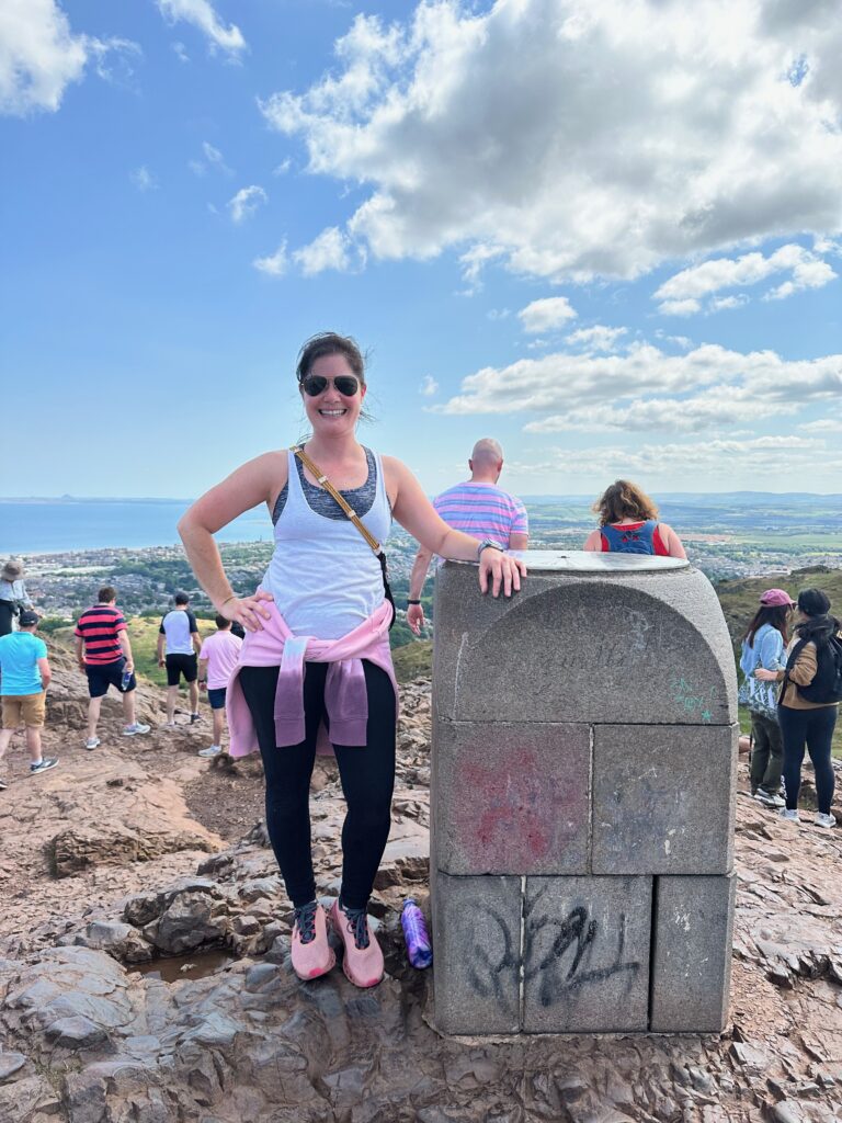 Kimberly standing next to a small pillar that could be Arthur's Seat. 